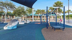 Un parque infantil con tobogán, estructuras para escalar y un banco.