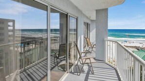 A balcony with a view of the beach and ocean.