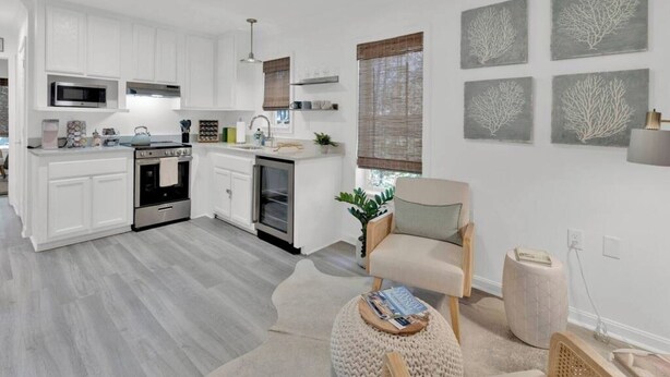 A modern kitchen with white cabinetry, stainless steel appliances, and a central island.