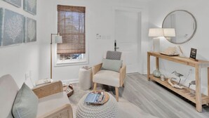A modern living room with a sofa, armchair, and coffee table, a wooden console table with decorative items, and artwork on the walls.