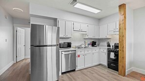 Una cocina moderna con electrodomésticos de acero inoxidable, armarios blancos y una pared de acento de madera.