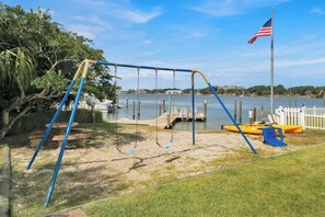 Enjoy a serene lakeside retreat with a swing and dock area surrounded by lush greenery.