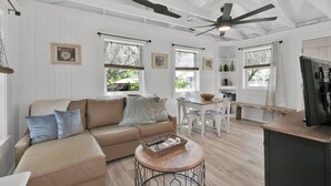 A spacious living area with a beige sofa, a round coffee table, and a ceiling fan.
