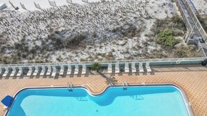 Vista aérea de una piscina con playa de arena y muelle de madera con sillas de descanso.