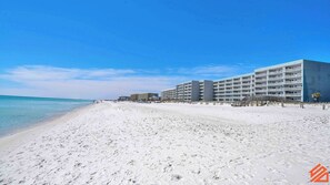 A beachfront hotel with multiple floors, a sandy beach in the foreground, and a clear blue sky. - Okaloosa Island Gulf View Resort Studio w/ Balcony (Fort Walton Beach)