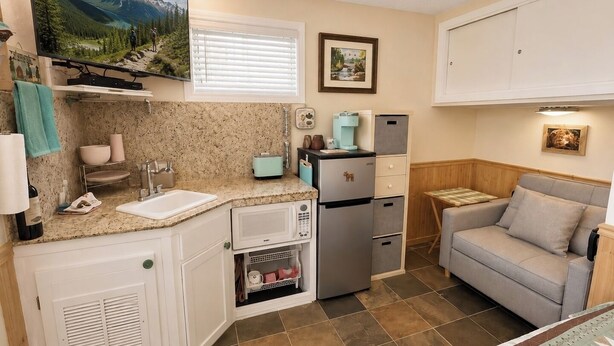 Cocina compacta con lavaplatos, microondas, tostadora y refrigerador.