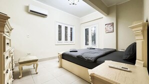 Ein Schlafzimmer mit Bett, Kommode, Sessel und Klimaanlage.
