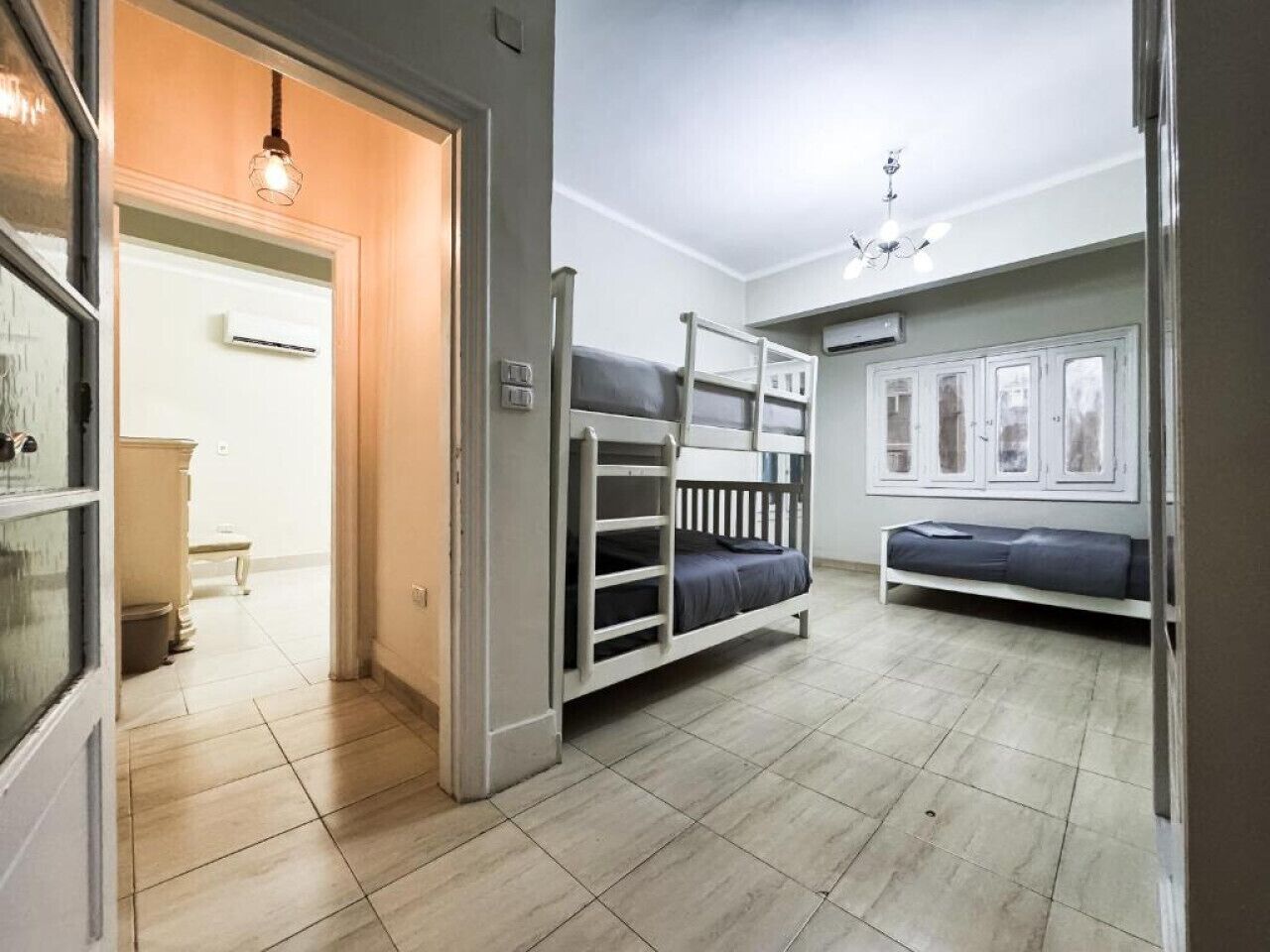 A room with bunk beds, a small seating area, and a door leading to another room.