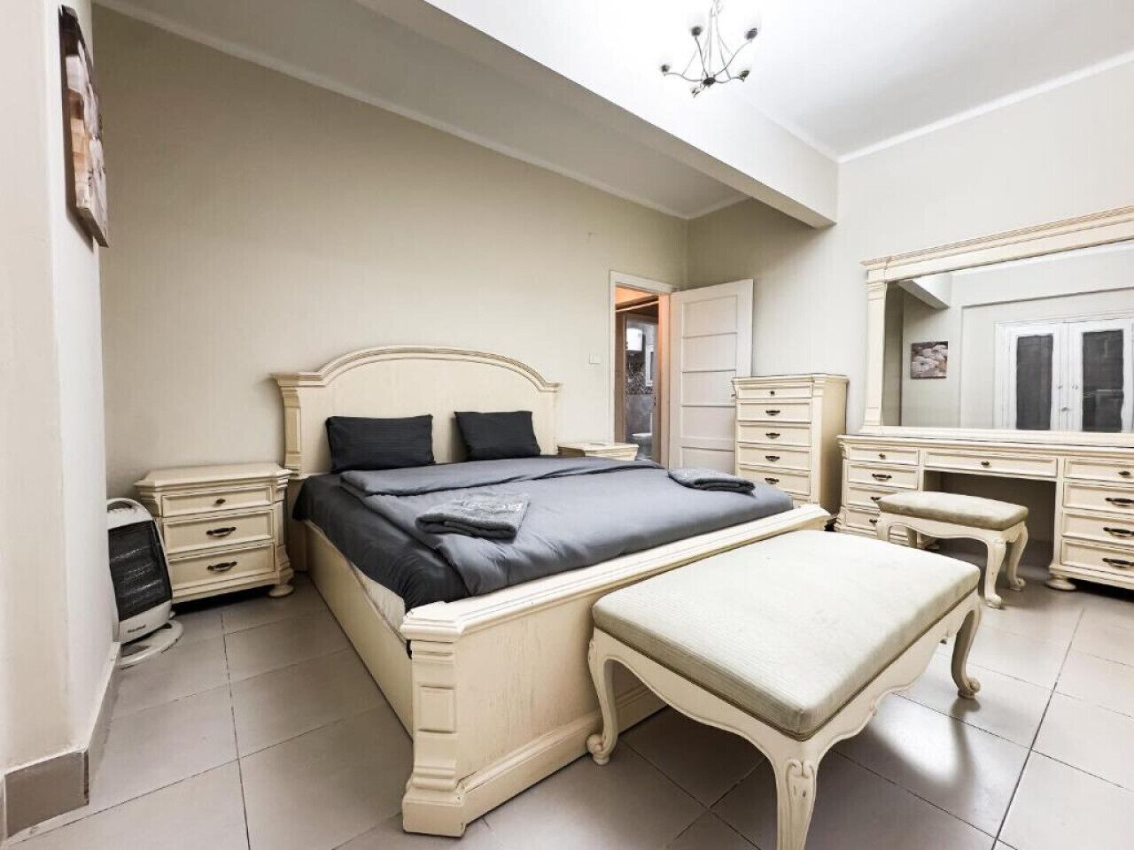 A bedroom with a large bed, bedside tables, a dresser, and a mirror.