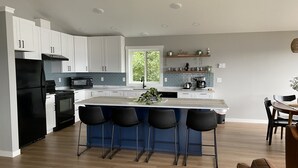 A modern kitchen with white cabinets, a black refrigerator, and a central island with bar stools. - Nordic House (Petersburg)