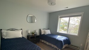 A bedroom with two beds, a bedside table, a mirror, and a window. - Nordic House (Petersburg)