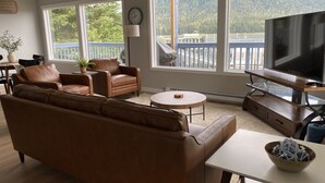 A living room with a brown leather sofa, a round coffee table, and a TV on a wooden stand. - Nordic House (Petersburg)