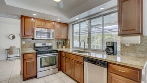 Una cocina moderna con armarios de madera, electrodomésticos de acero inoxidable y un ventanal amplio.