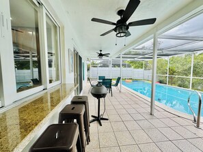 Ein überdachter Patio-Bereich mit Pool, Sitzgelegenheiten und Deckenventilatoren.