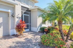 Stunning home with a well-manicured yard and modern design, featuring a large garage door and vibrant plants.