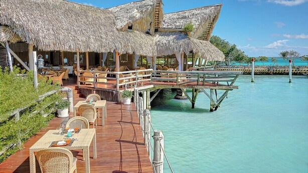 Des bungalows sur pilotis dotés de toits de chaume, de terrasses en bois et offrant une vue sur la mer turquoise.