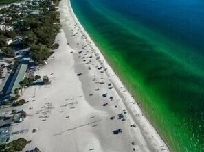 An aerial view of a beach with clear turquoise water, sandy shore, and scattered buildings. - Villa Rozafa
Cozy,spacious,walking distance from downtown white sandy beach. (Anna Maria)