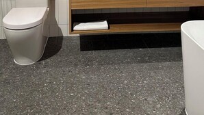 Een moderne badkamer met een wit toilet, een houten wastafelmeubel met een wastafel en twee spiegels aan de muur.