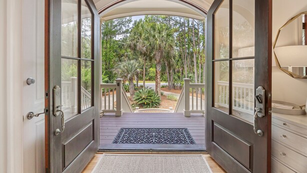 A view from a porch with a wooden deck leading to a door with glass panels.