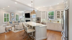A spacious kitchen with a central island, white cabinetry, and modern appliances.