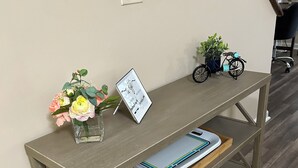 Uma mesa de madeira com um vaso de flores, uma moldura com uma frase inspiradora e um caderno.