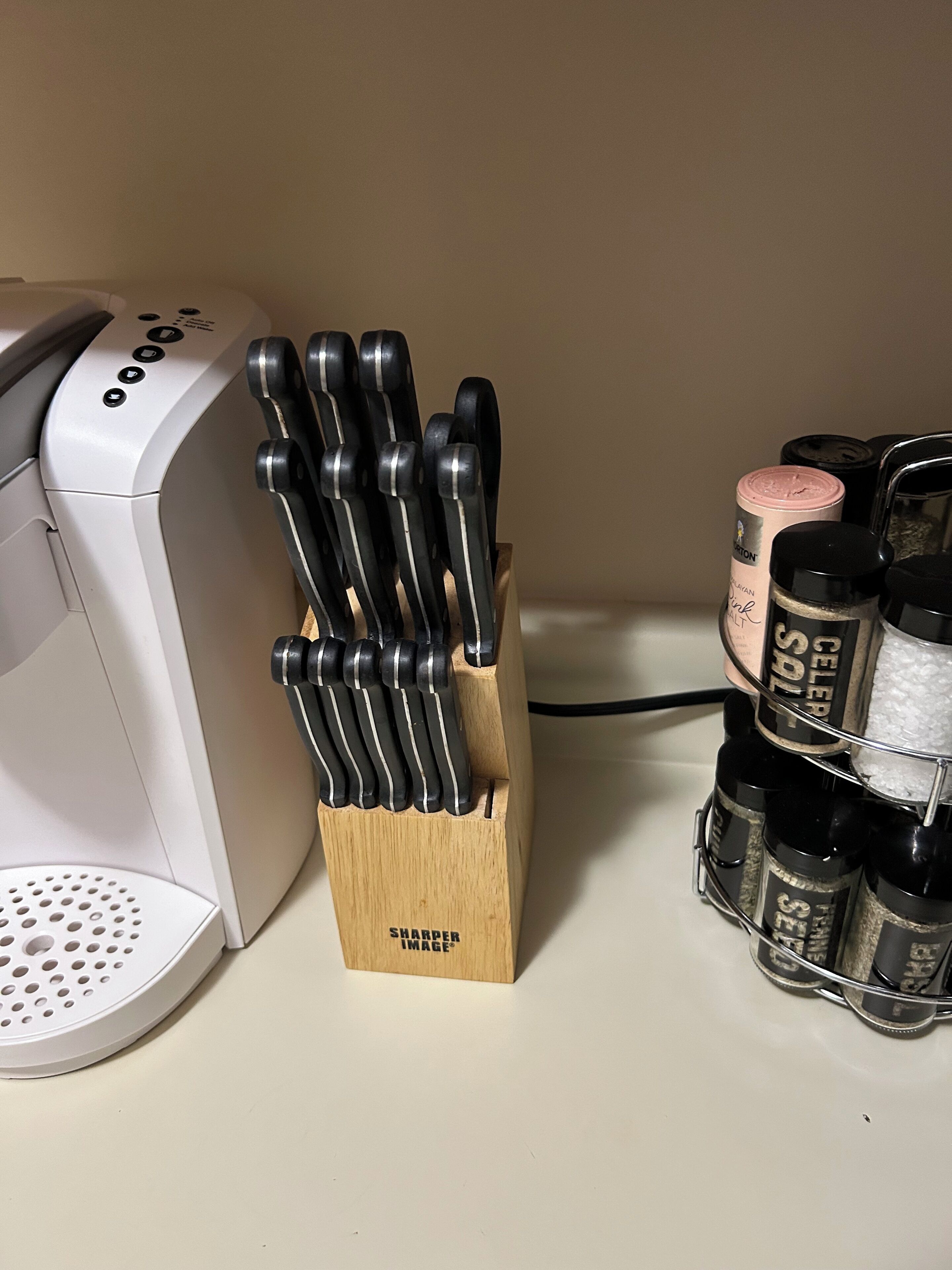 A kitchen counter with a coffee maker, a knife block, and spice containers.