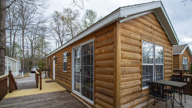 A log cabin with a deck, large windows, and a table with chairs. - Story-time Stay at Our Rupert Cottage! (Monteagle)