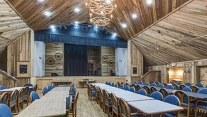A conference room with long tables and chairs, wooden walls, and a chandelier. - Story-time Stay at Our Rupert Cottage! (Monteagle)