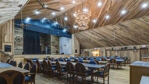 A spacious hall with multiple tables and chairs, wooden walls, and a high ceiling with exposed beams. - Story-time Stay at Our Rupert Cottage! (Monteagle)