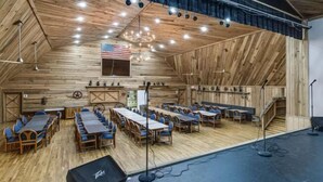 A rustic barn-style venue with wooden walls and a sloped ceiling, equipped with tables and chairs for dining or events. - Story-time Stay at Our Rupert Cottage! (Monteagle)