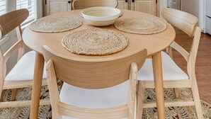 Uma cozinha com armários de madeira, uma geladeira branca e uma mesa de jantar com jogos americanos trançados.