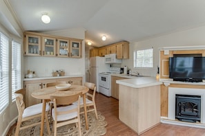 A modern kitchen with wooden cabinets, a central island, a built-in microwave, and a fireplace.