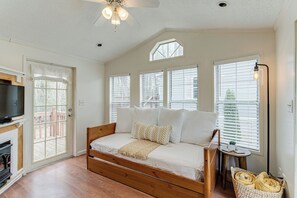 A bedroom with a wooden bed, white bedding, a television, and a window with blinds.