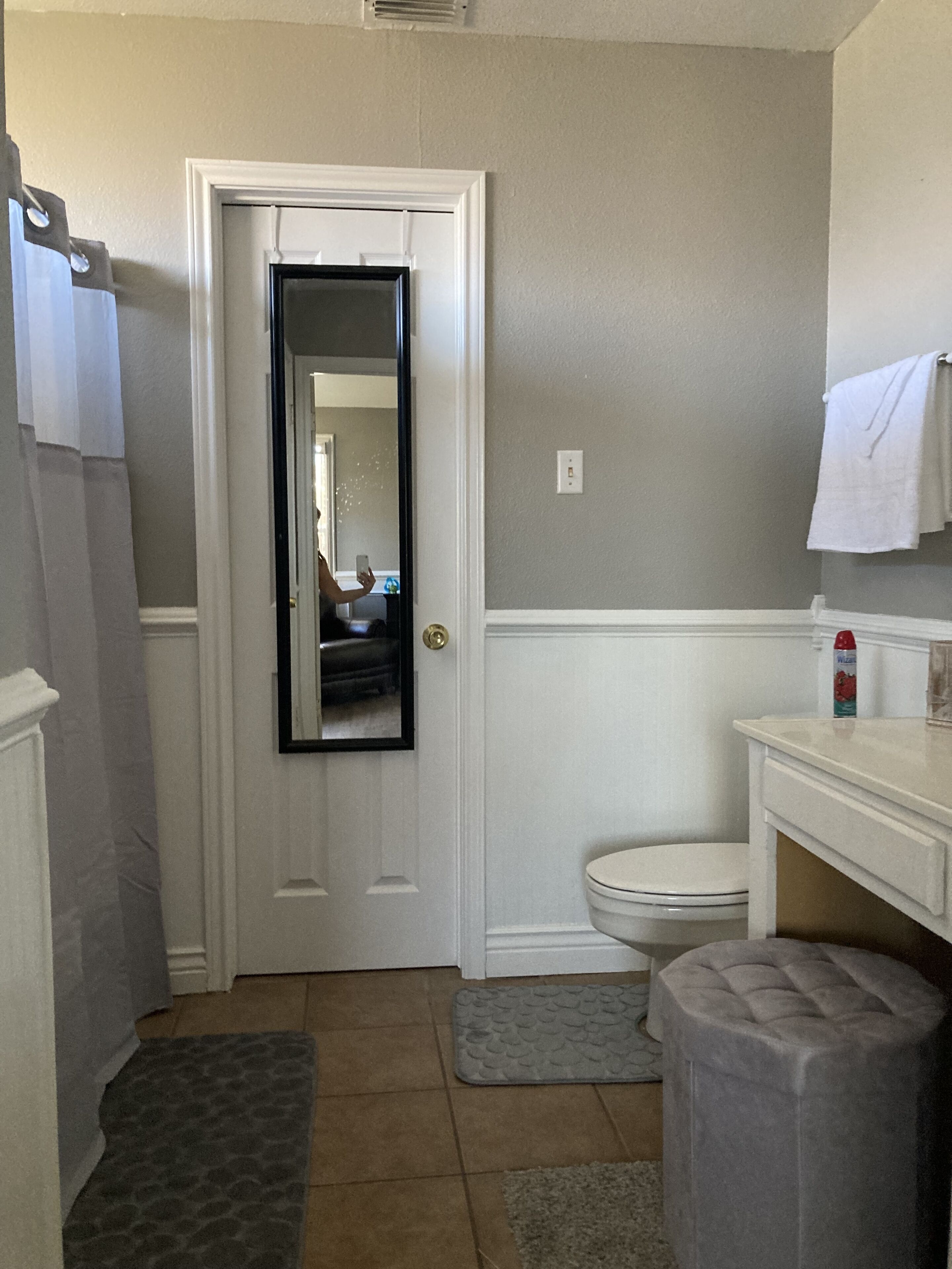 A bathroom with a white door, a toilet, a sink, and a mirror.