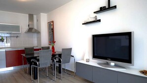 Una cocina moderna con comedor, un televisor de pantalla plana grande y estanterías empotradas.