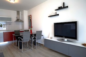 Et moderne køkken med spiseplads, stort fladskærms-TV og indbyggede hylder.