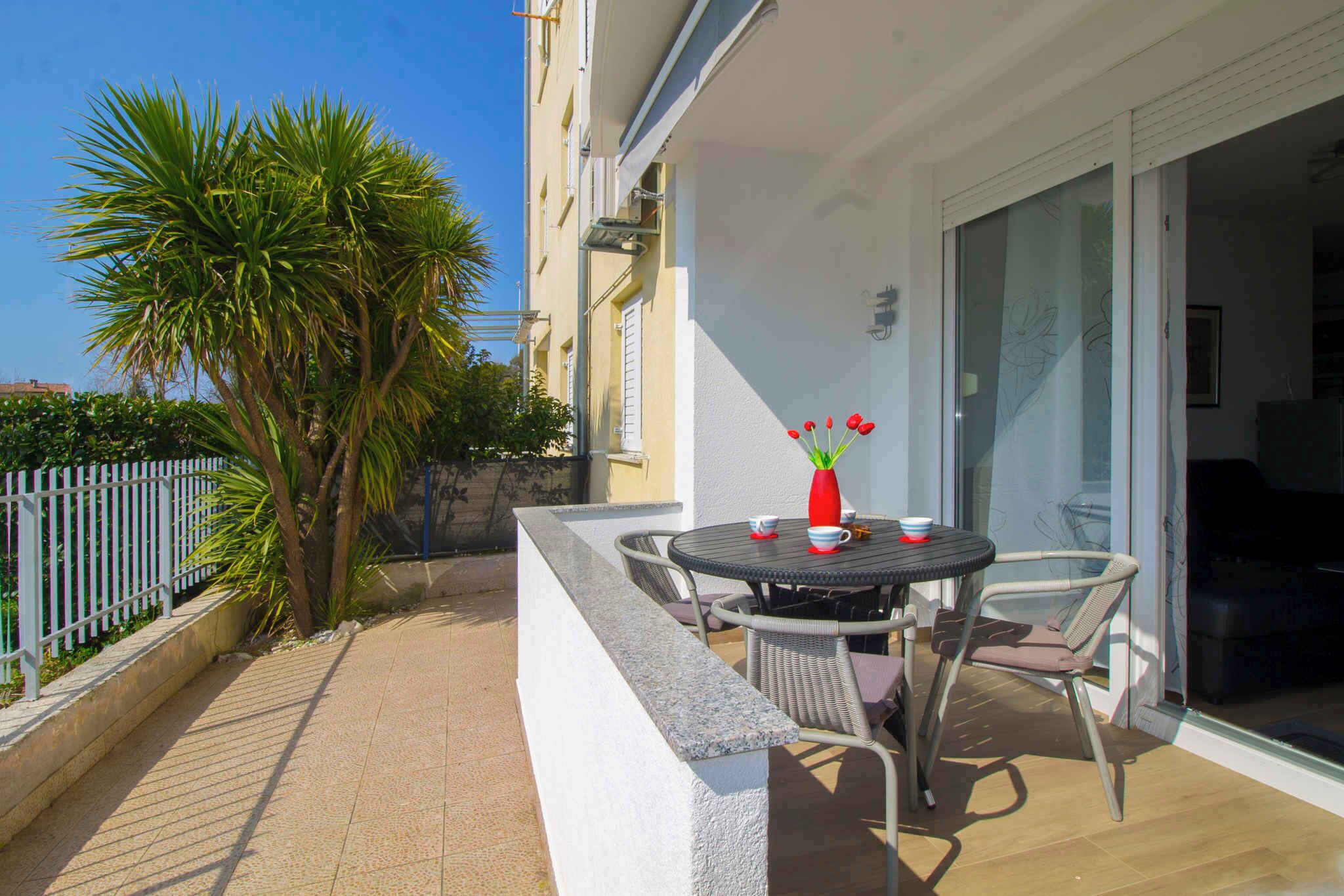 Ein Balkon mit Tisch, Stühlen, einer Blumenvase und einer Palme.