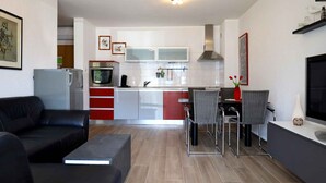 Una cocina moderna con comedor, un sofá de cuero negro y un televisor de pantalla plana.