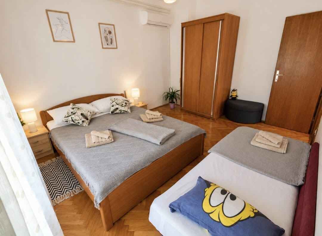 A bedroom with a bed, bedside tables, a wardrobe, and a small table with a plant.