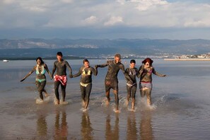 Un grupo de personas corriendo en aguas poco profundas, con un paisaje montañoso al fondo.