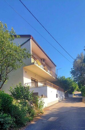 Un edificio residencial de dos pisos con un balcón en el nivel superior.