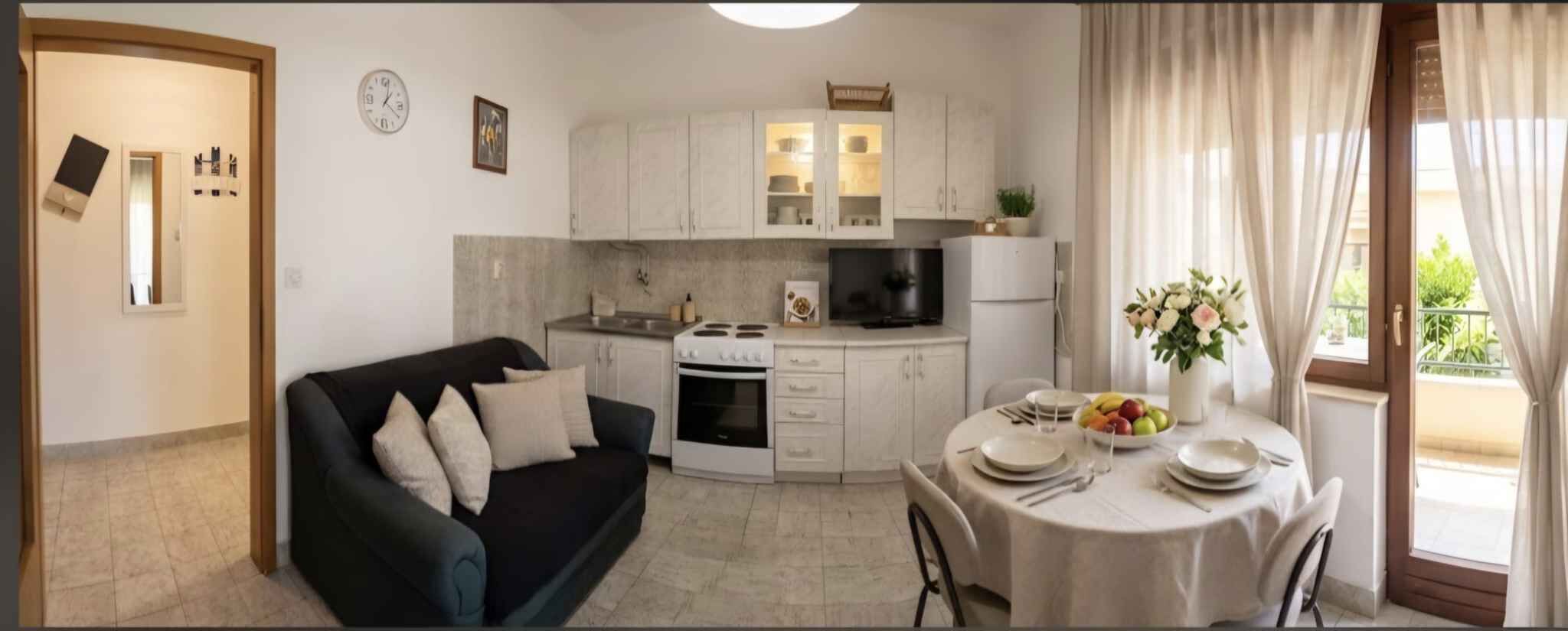A compact living space with a kitchenette, a dining area, and a sofa.