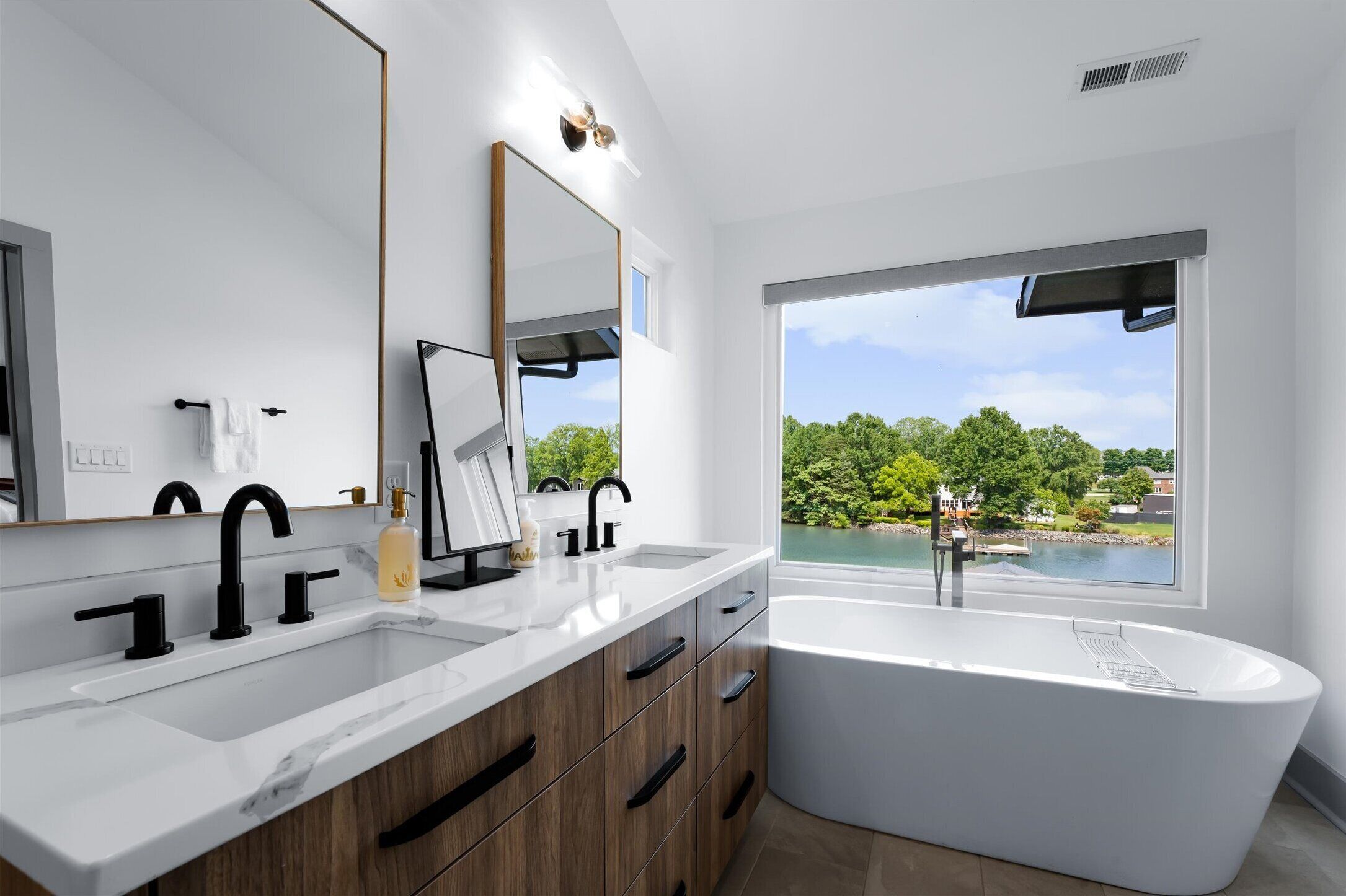 Une salle de bain moderne avec une baignoire sur pieds, un grand miroir et une fenêtre offrant une vue panoramique.