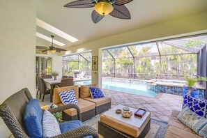 A sunlit patio with wicker furniture, a pool, and a view of palm trees. - Fort Myers Vacation Rental w/ Lanai & Private Pool (Fort Myers)