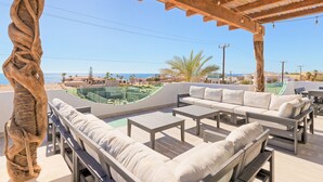An outdoor seating area with a view of the sea and a pool.