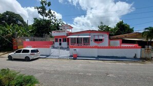Un bâtiment à la façade rouge et blanche, doté d’une entrée fermée par un portail et devant lequel est garée une voiture blanche.