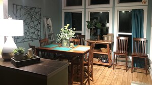 Un coin repas accueillant avec une table et des chaises en bois, un vase de fleurs et une échelle appuyée contre le mur.