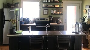 Une cuisine dotée d’un îlot central, de poutres en bois au plafond et d’un mur vert.