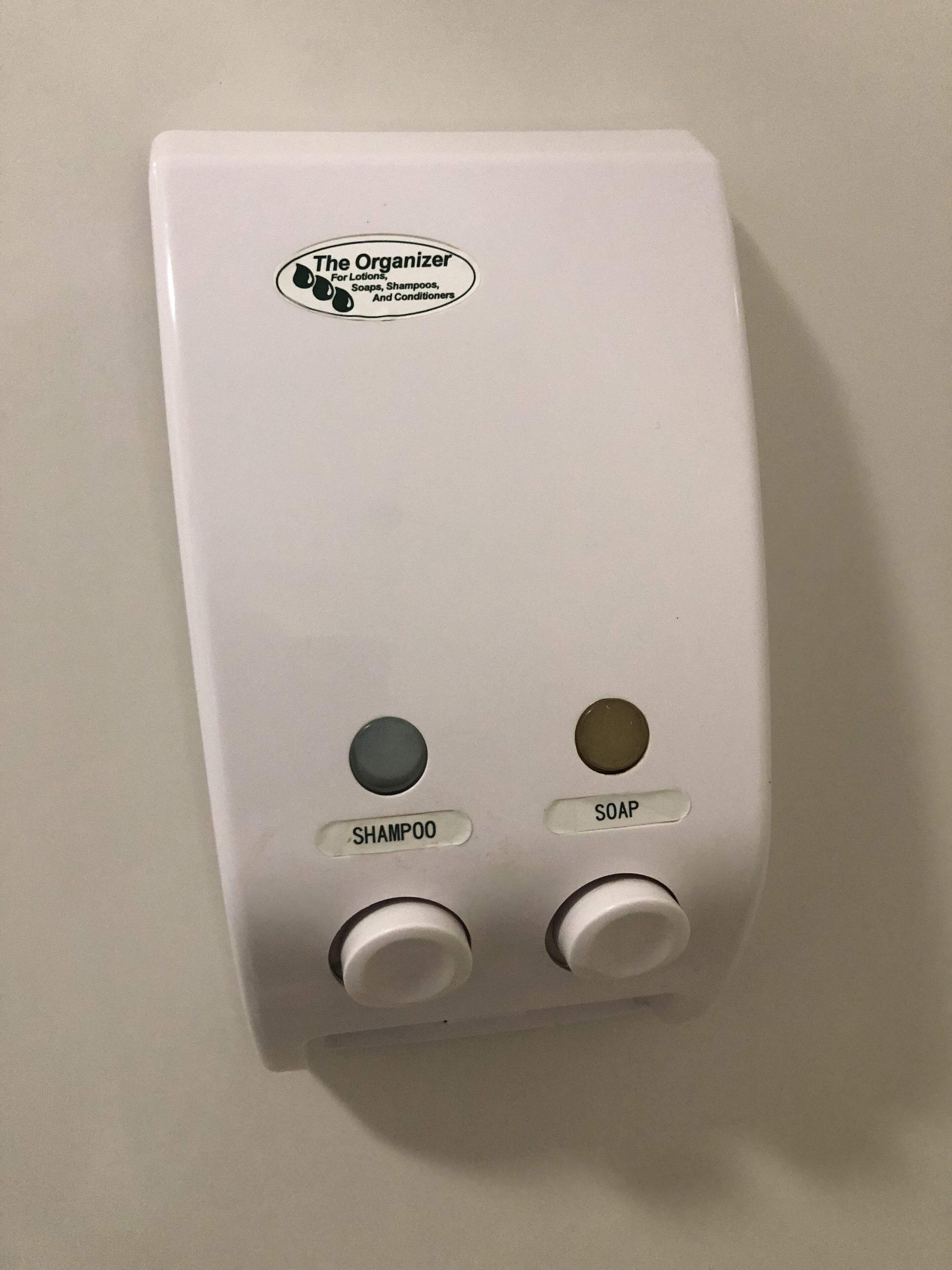 A wall-mounted soap dispenser with two buttons labeled "SHAMPOO" and "SOAP".