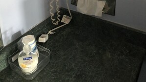 Un baño con secador de pelo, dispensador de toallas, dispensador de jabón y secamanos sobre una encimera de mármol.